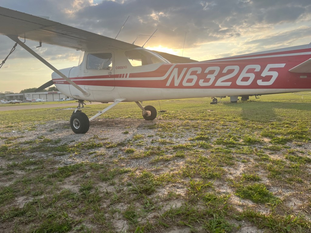 Cessna 150M Commuter training aircraft parked on grass at sunset, showing side profile and tail number at Zephyrhills Municipal Airport (KZPH) at Central Florida Flight Training.
